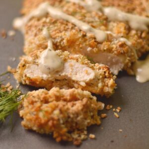 Panko crusted chicken breast cut into pieces with ranch on top.