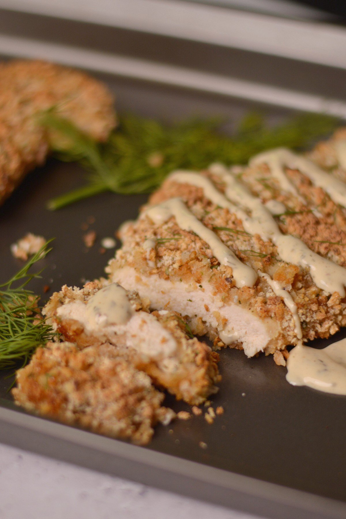 Panko crusted chicken breast cut into pieces with ranch on top.