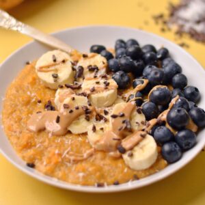 Sweet potato porridge with bananas, blueberries, and cashew butter on top.