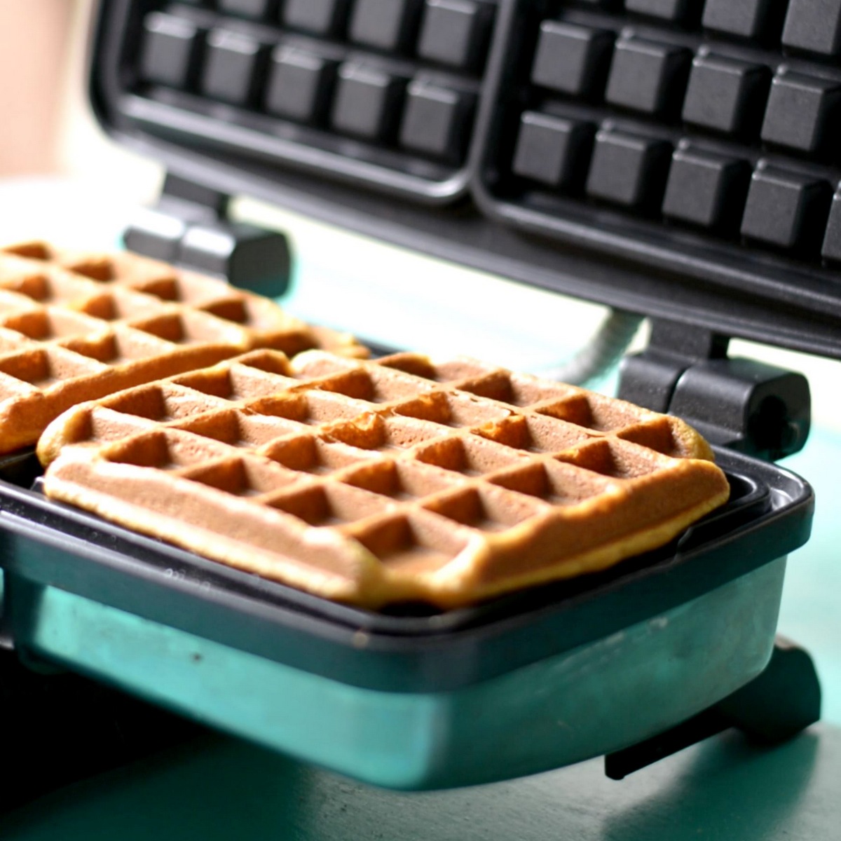 A cooked sweet potato waffle in a waffle iron.