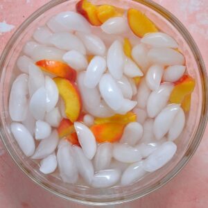 A bowl with ice cubes and peach slices.