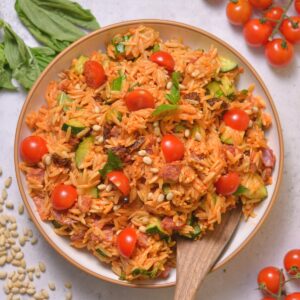 Red pesto pasta salad with basil, tomatoes, and pine nuts.