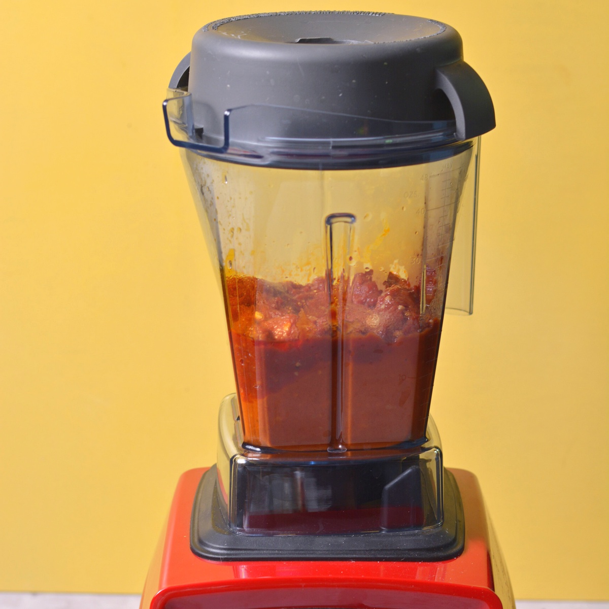 A blender with red pesto inside.
