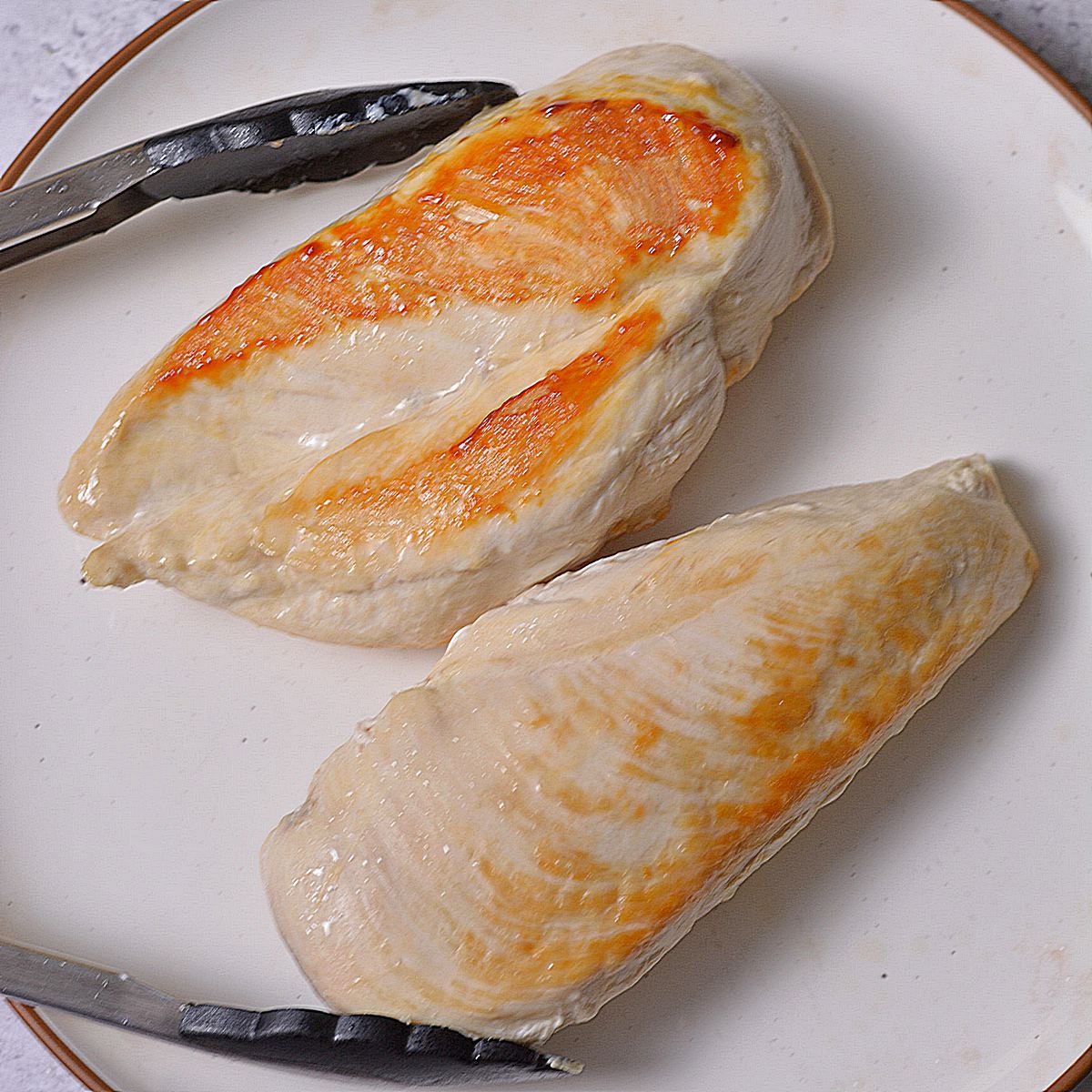 Cooked chicken breasts on a white plate.