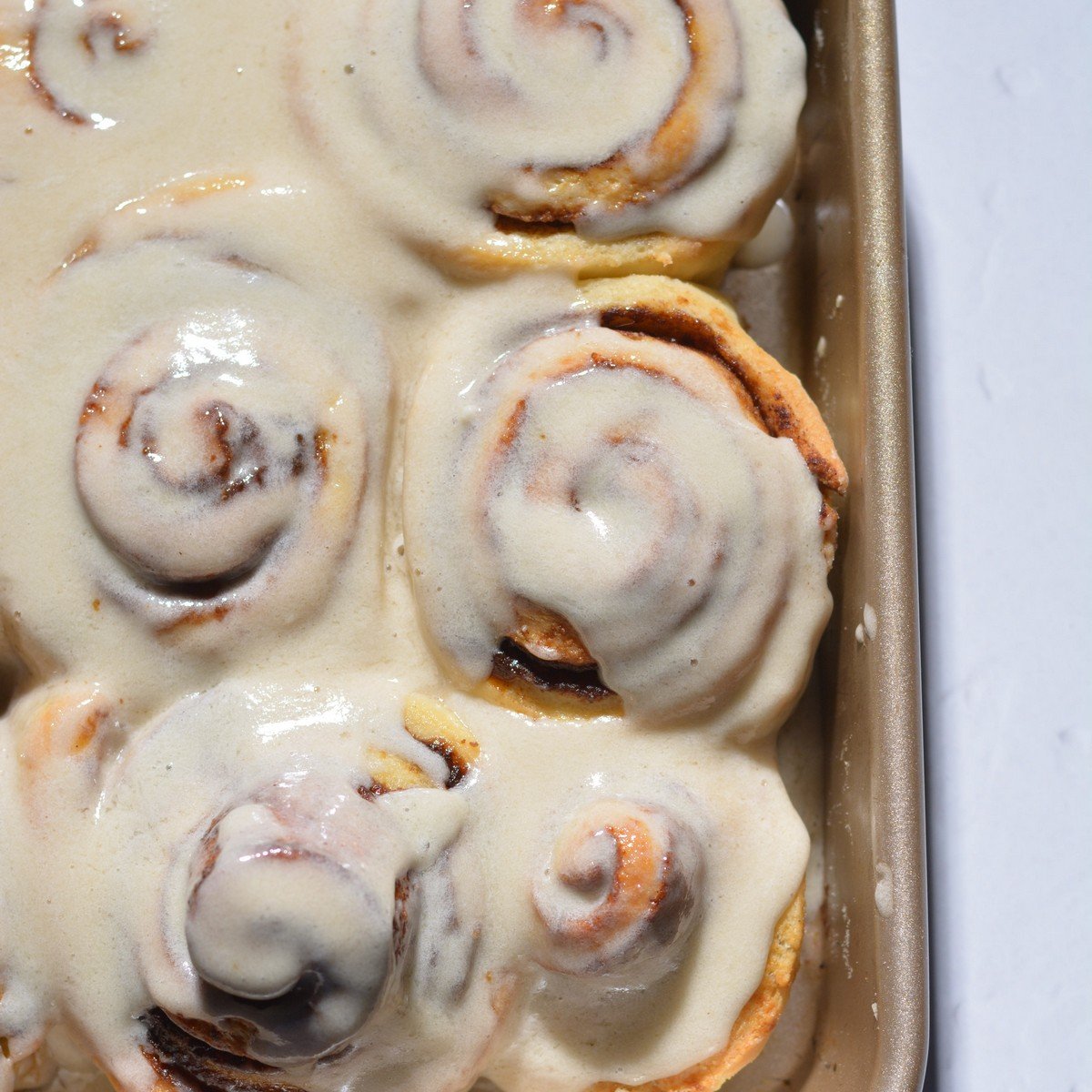 Protein cinnamon rolls with a cream cheese frosting in a pan.