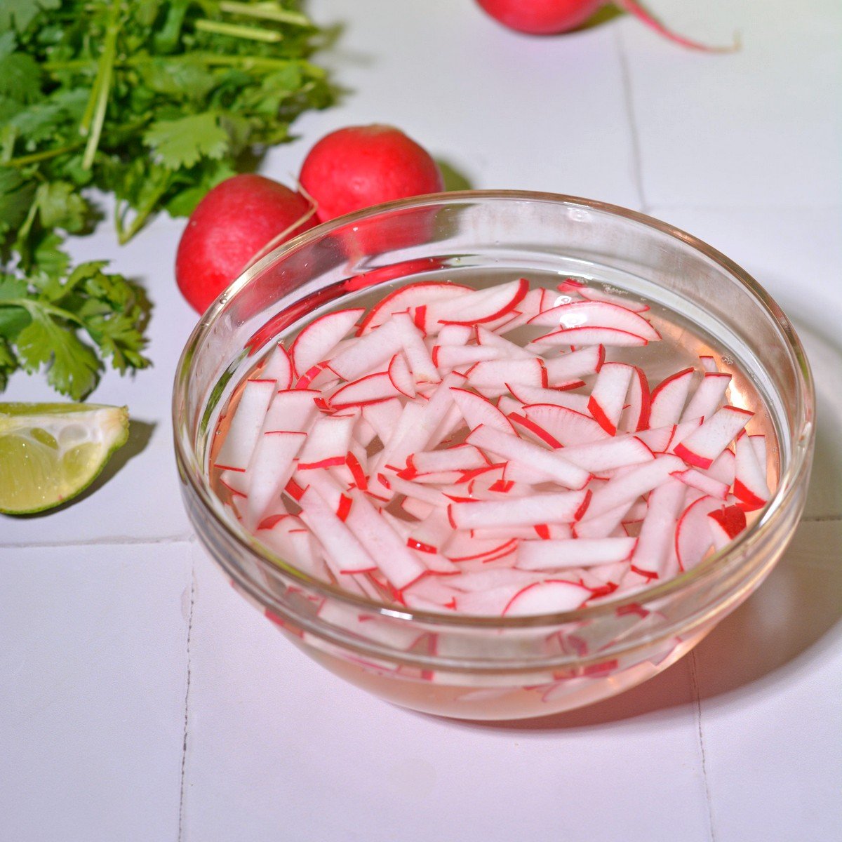 Pickled radishes in a glass bowl in the water vinegar mixture.