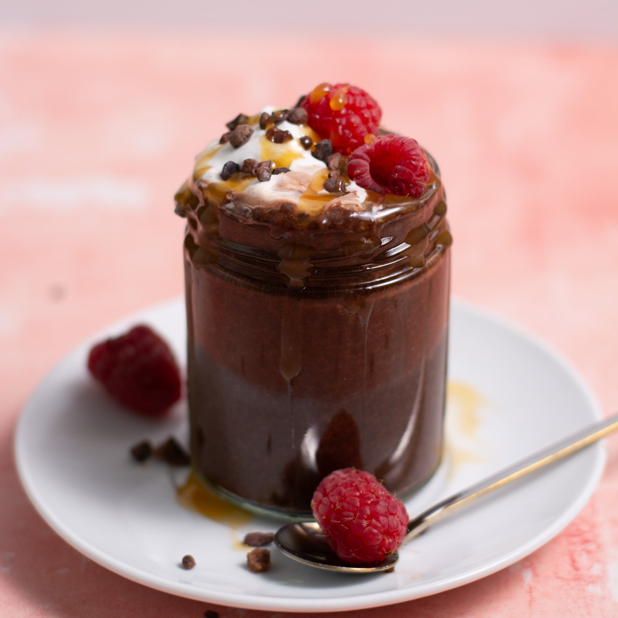 chocolate chia seed pudding on a jar with whipped cream and raspberries.
