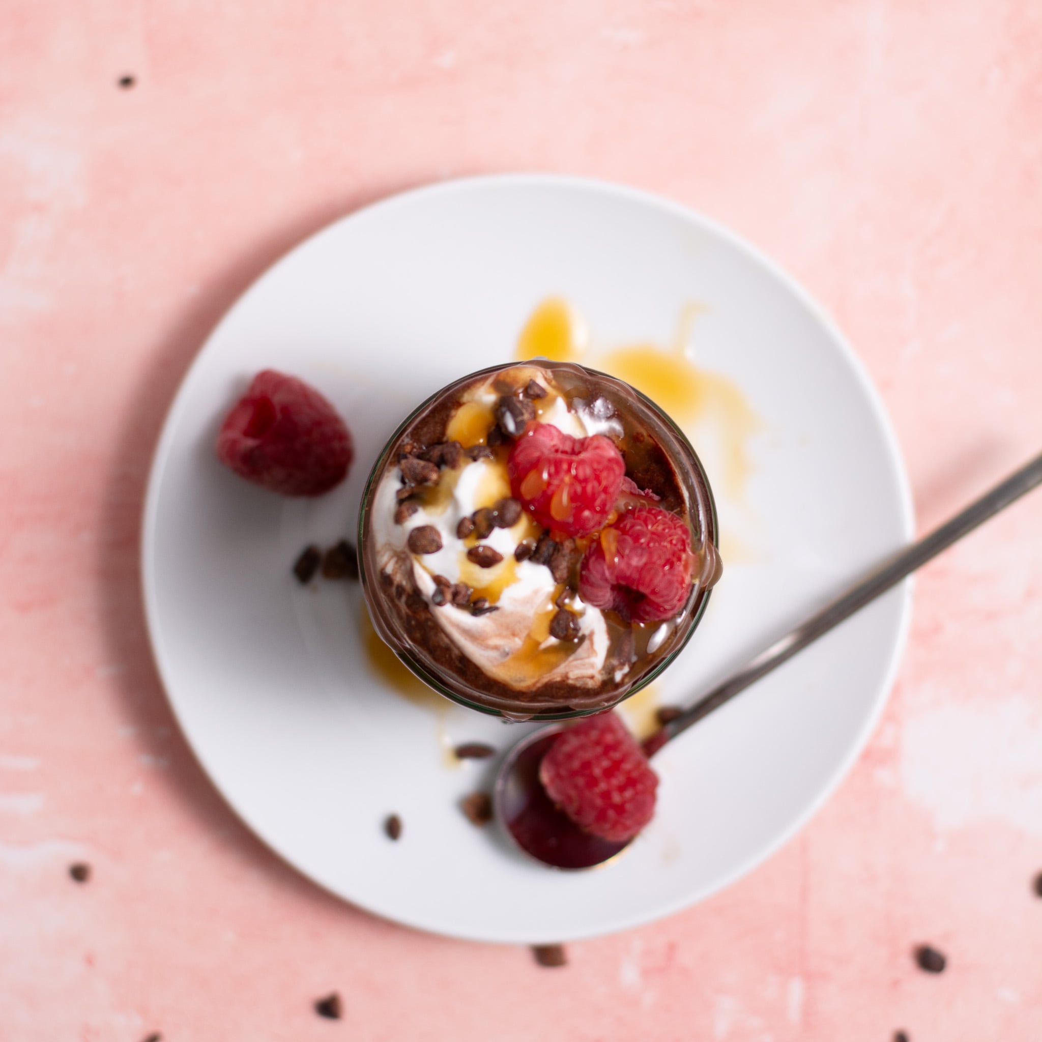 chocolate chia seed pudding on a jar with whipped cream and raspberries.