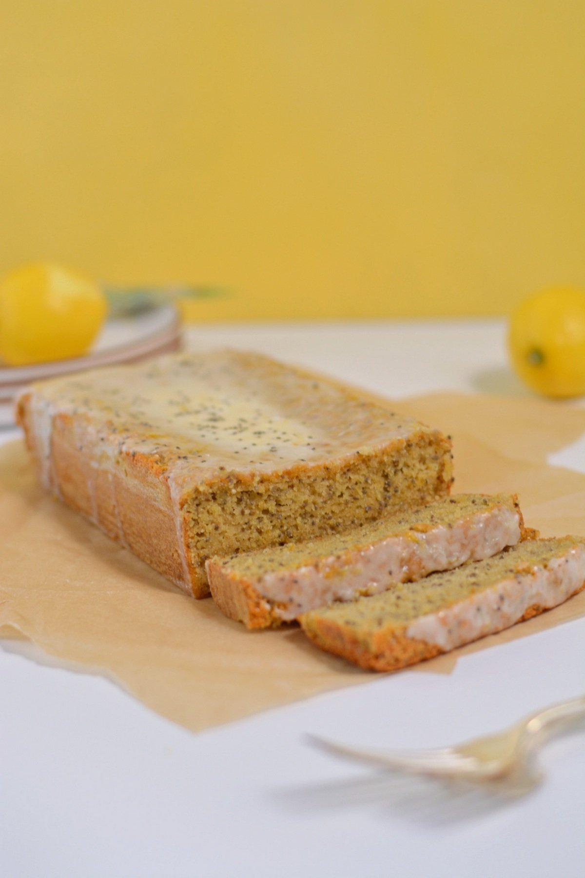 Protein lemon bread sliced in front of a yellow background.