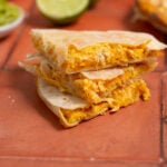 A stack of protein breakfast quesadillas on a red tile background.