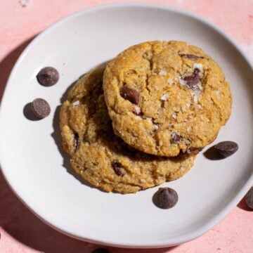 Two protein chocolate chip cookies on a plate.