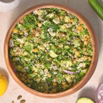 A green goddess salad with chickpeas, feta, quinoa, and green veggies in a wooden bowl.