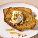 Two slices of pistachio bread with a dollop of Greek yogurt and crushed pistachios.