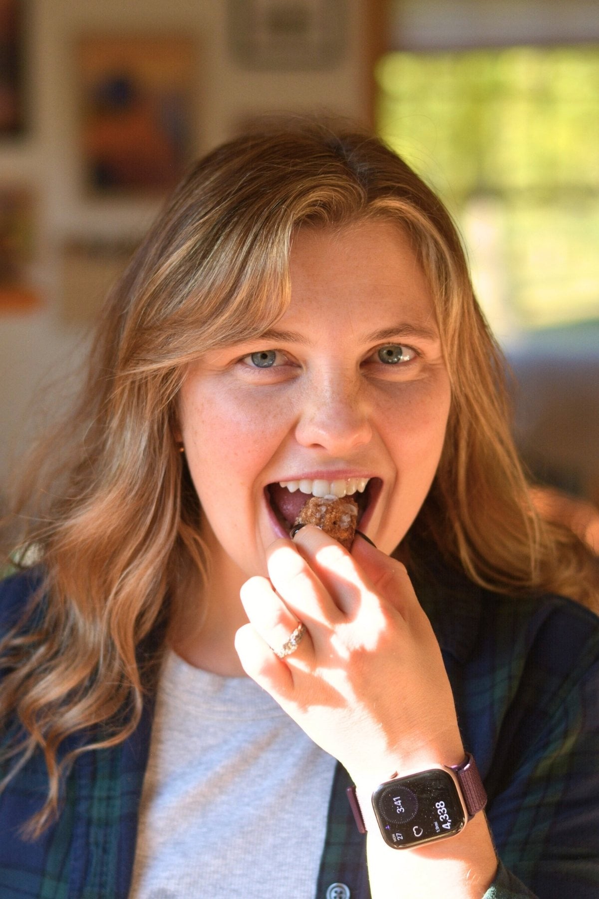 A beautiful woman eating a protein cinnamon roll bite.