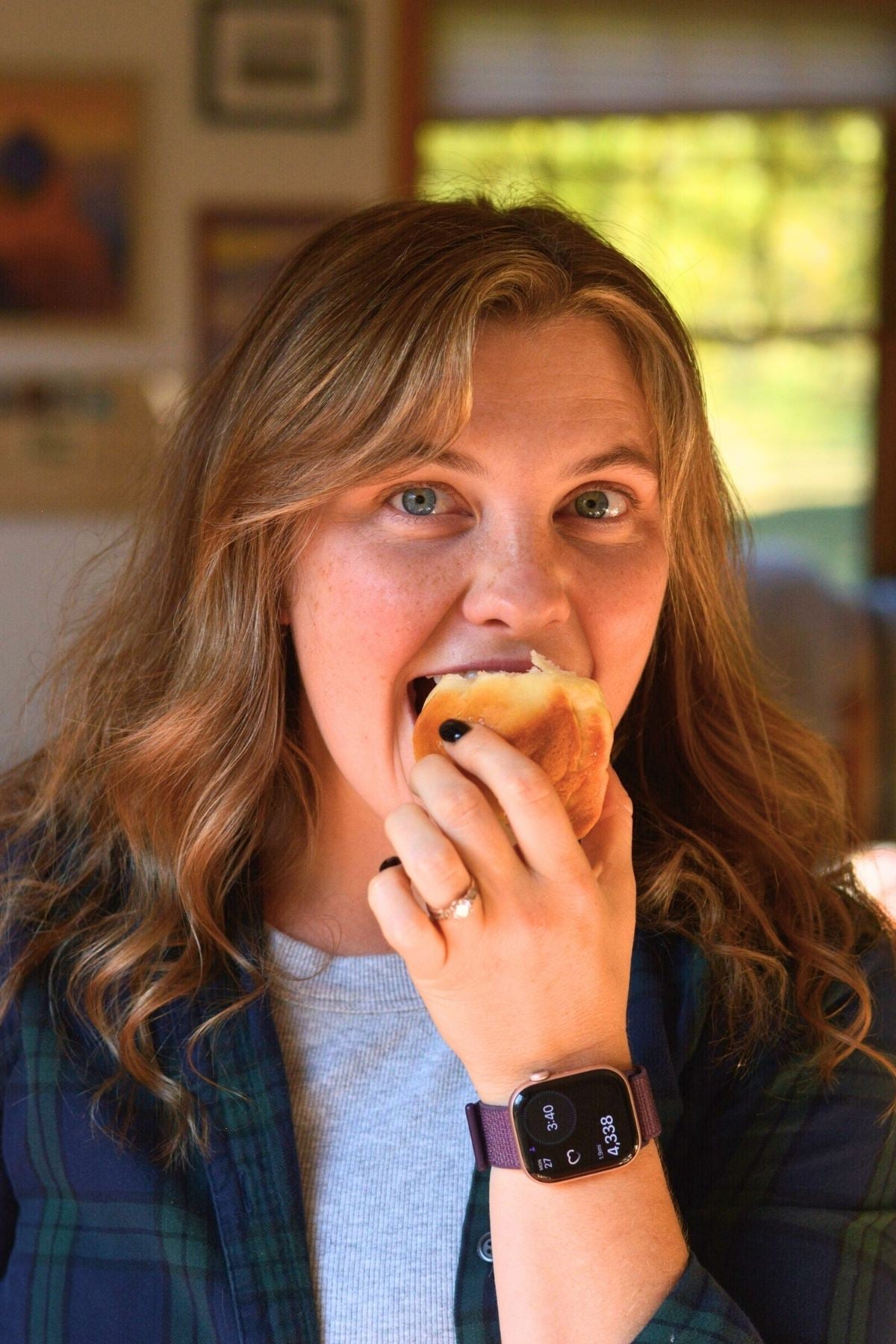 A beautiful woman taking a bite of a dinner roll.