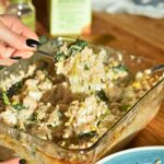 A fork picking up a scoop of white bean casserole with shredded basil on top.