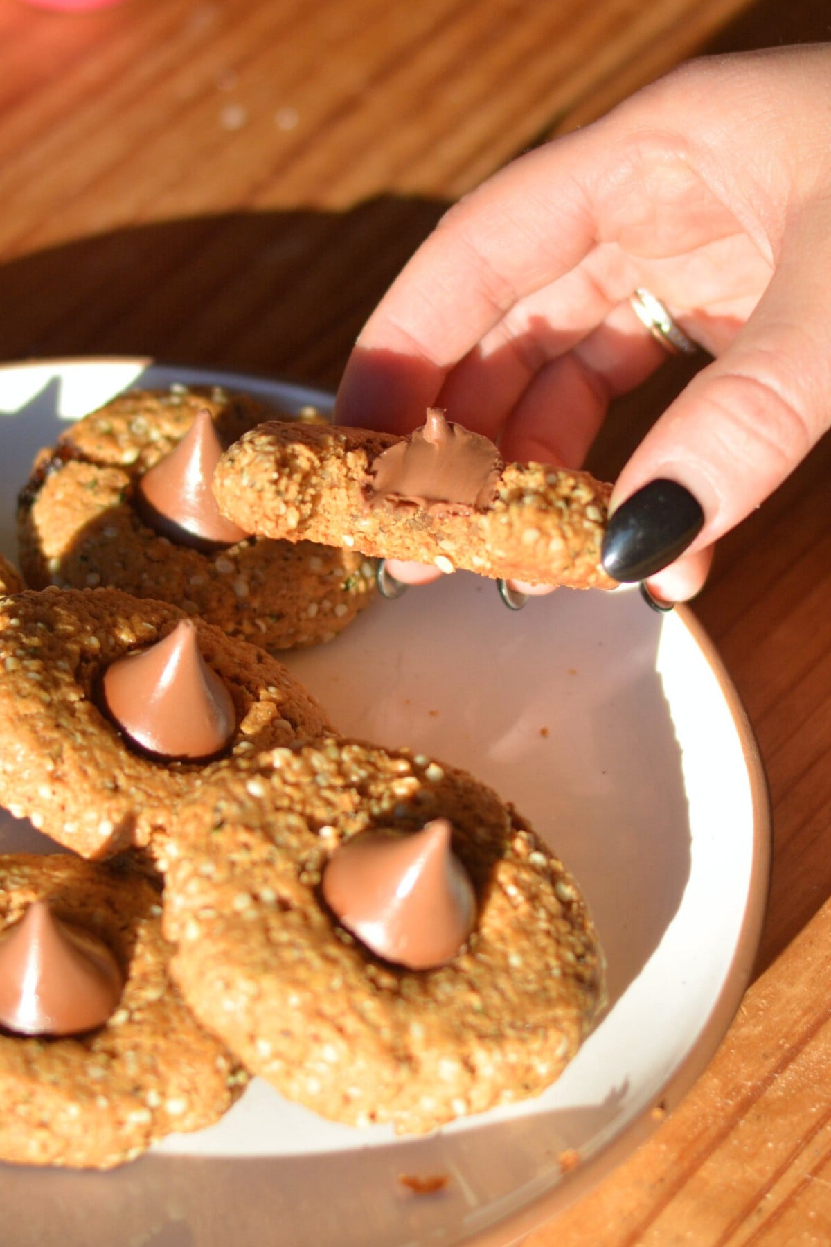 A hand holding the cookie with a bit taken out.