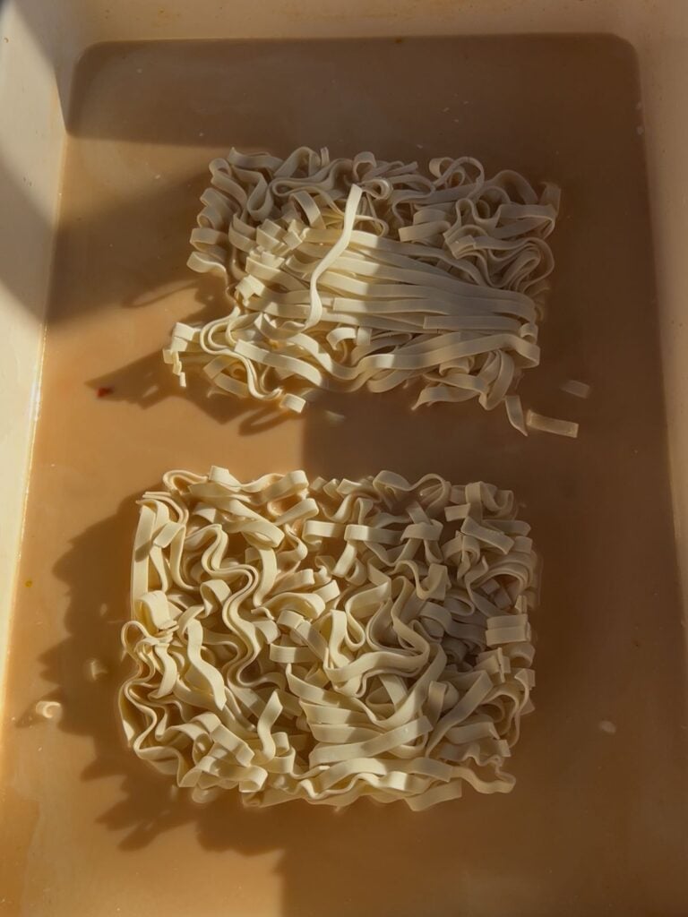 A pan with raw ramen noodles in a casserole dish.