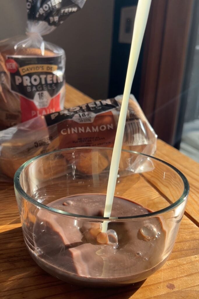 Pouring egg whites into the chocolate milk in the bowl.