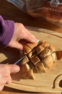Hands cutting up a bagel into small squares.