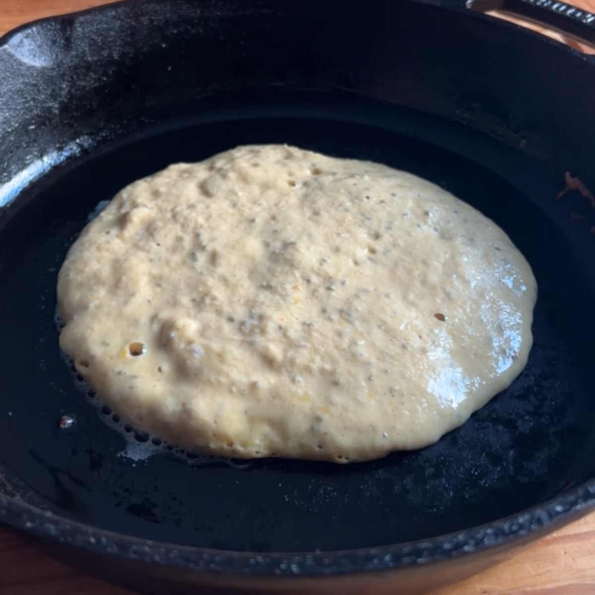 Orange pancakes cooking before flipping.
