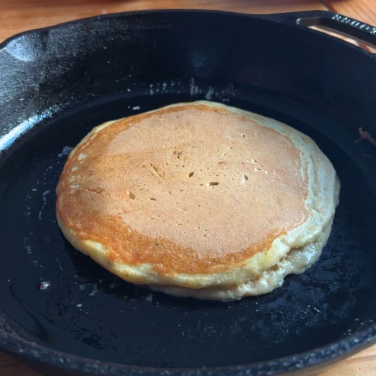 Orange pancakes cooking golden brown after flipping.