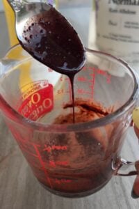 Spoon mixing the chocolate drizzle.