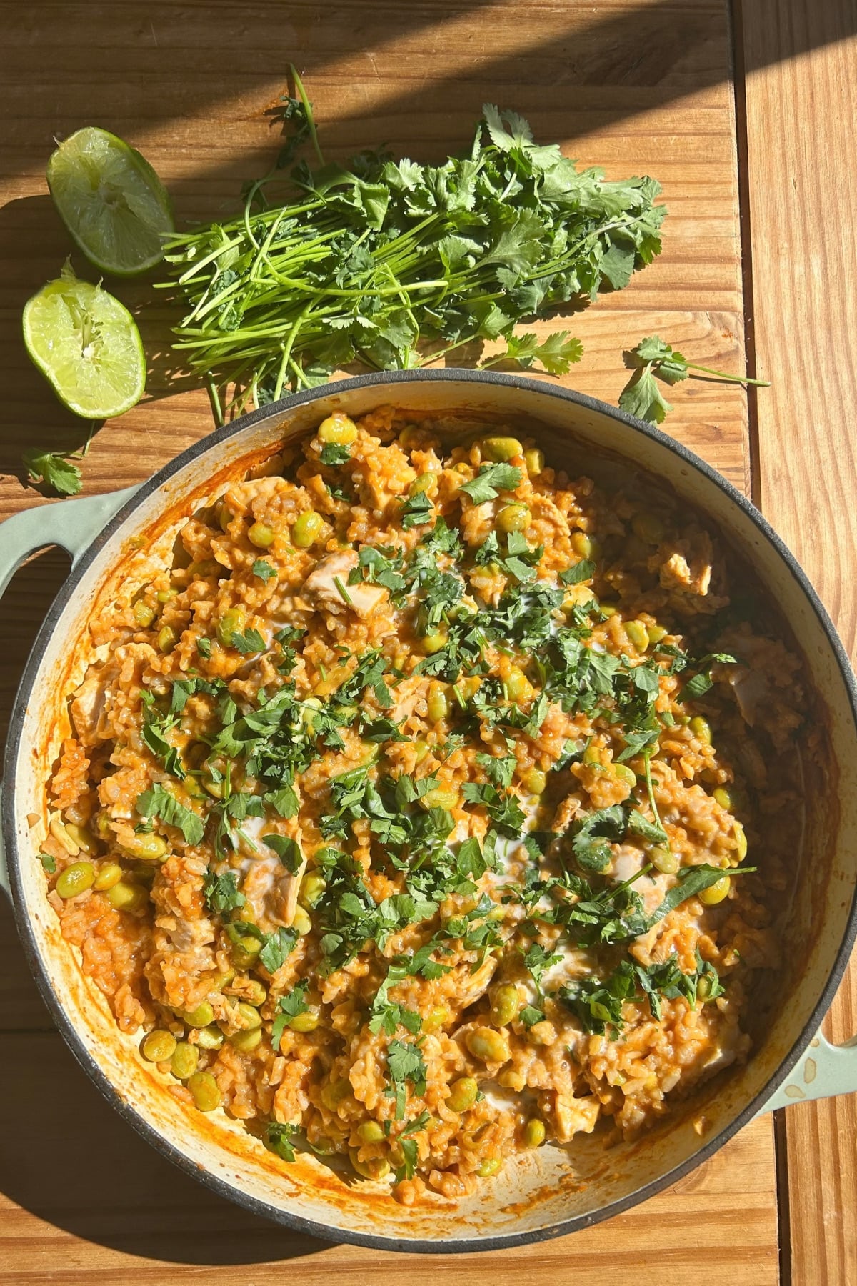 A braiser with crury chicken and rice and cilantro on top.