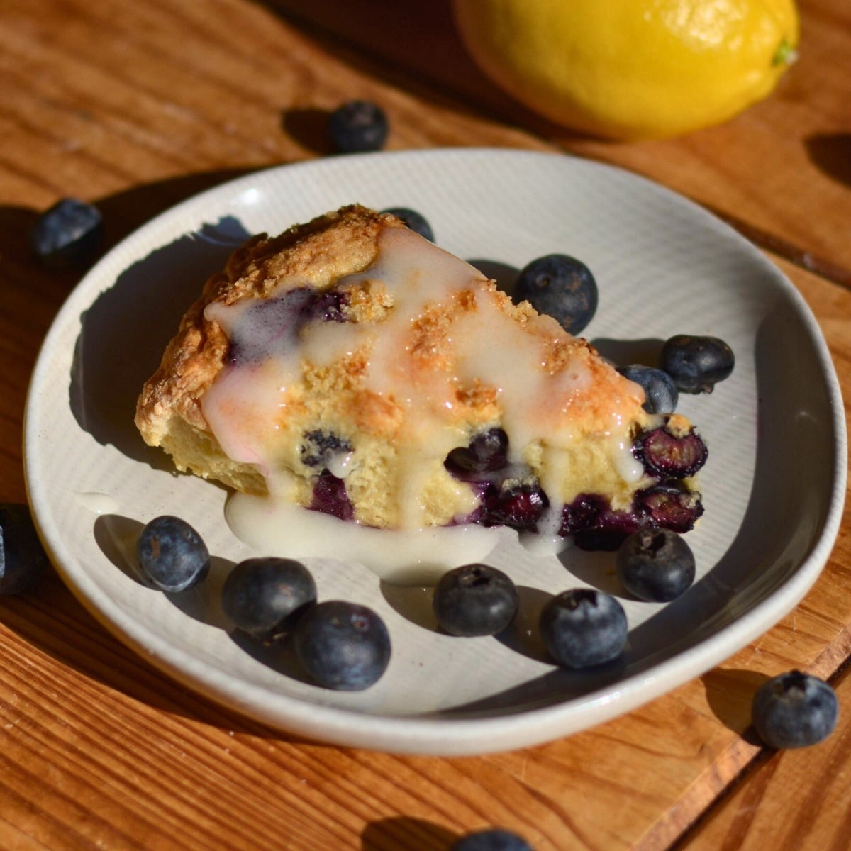 blueberry lemon cottage cheese scone on a plate with glaze.