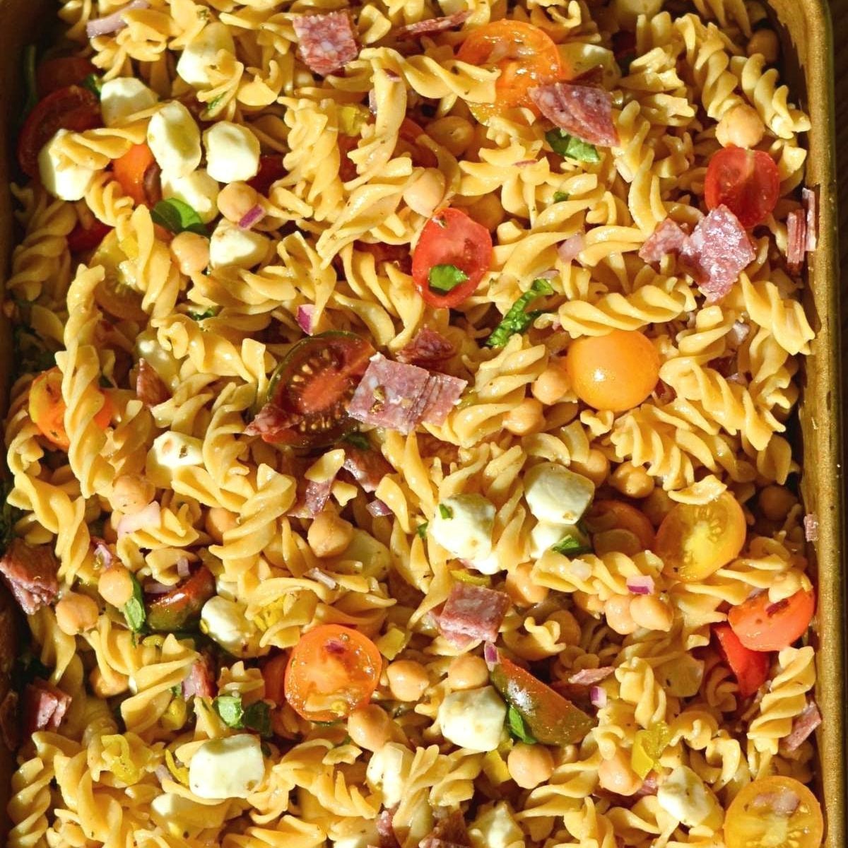 High-protein pasta salad with tomatoes, mozzarella pearls, salami, and chickpeas.