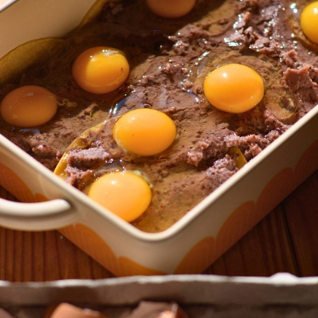 A casserole dish with eggs on top of refried black beans.