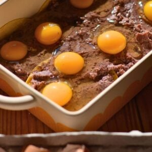 A casserole dish with eggs on top of refried black beans.