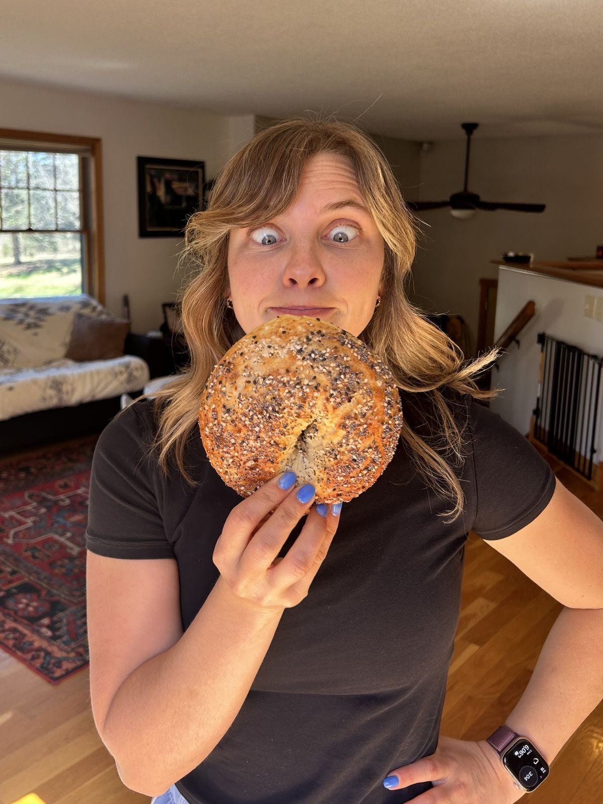 Mika holding a cottage cheese bagel to show its size next to her face.