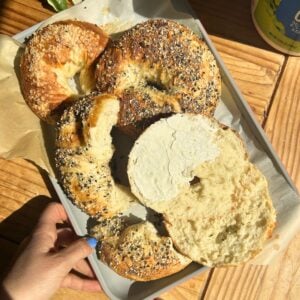 A tray with cottage cheese bagels and one with cream cheese spread on it.