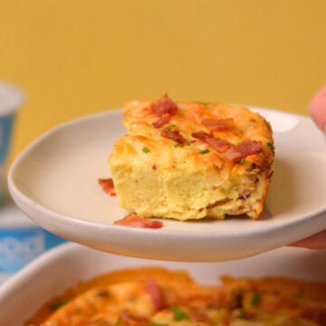 A hand holding a plate with a cottage cheese breakfast egg bake slice.