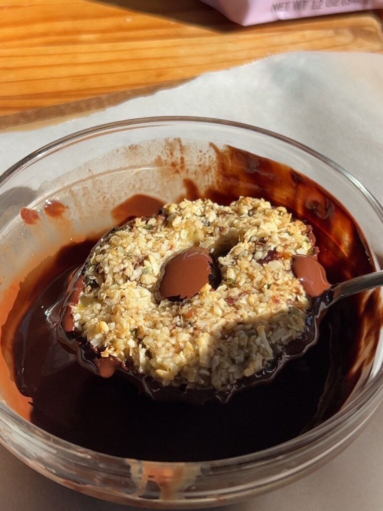 Cooked samoas being dipped in chocolate.