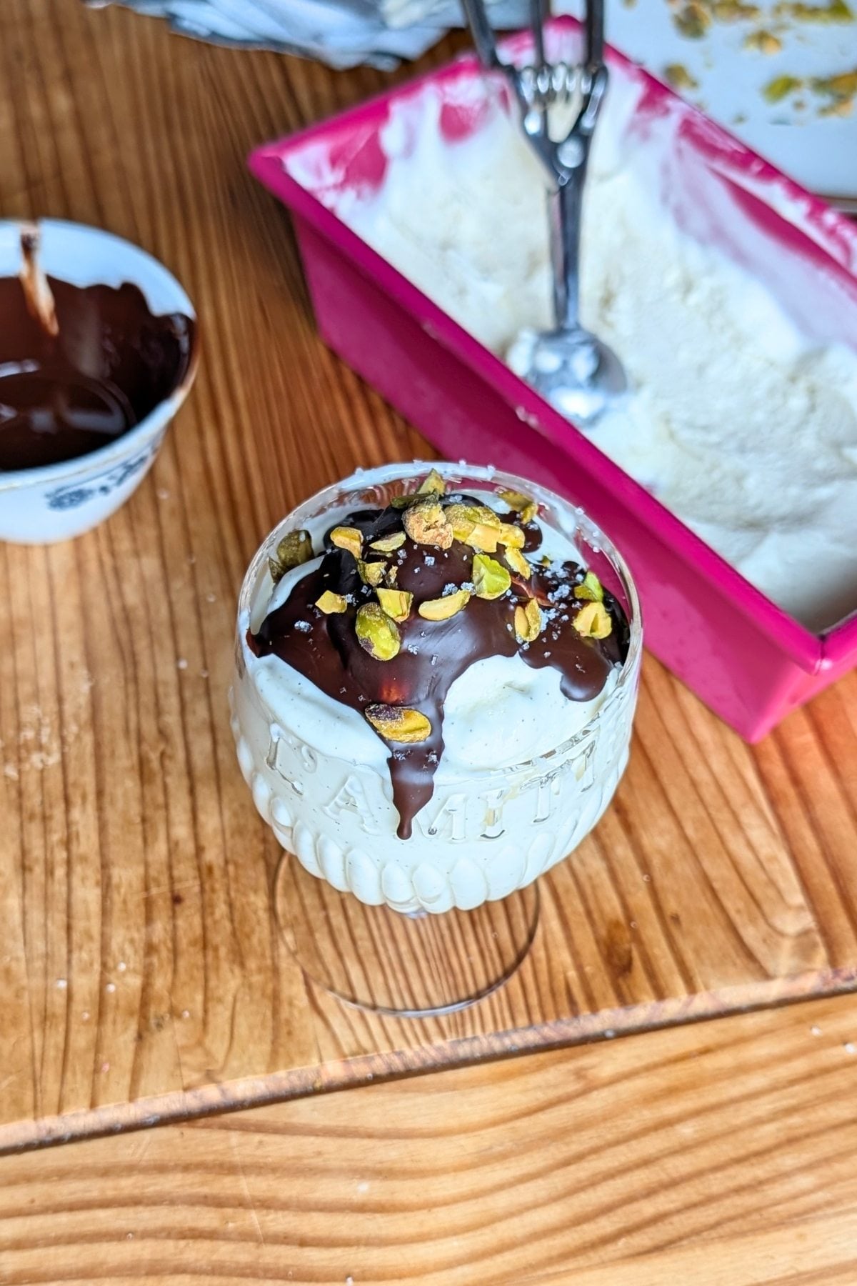 A cup with Greek yogurt ice cream with chocolate and pistachios on top.