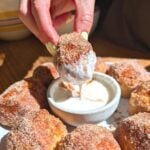 A hand dipping a protein pretzel bite into protein frosting.