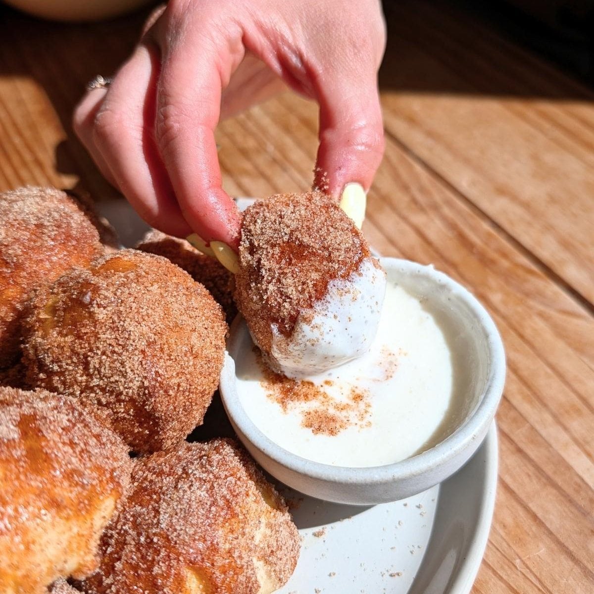 A hand dipping a protein pretzel bite into protein frosting.