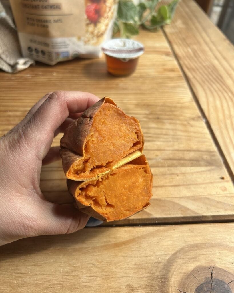Holding a cooked sweet potato sliced open.