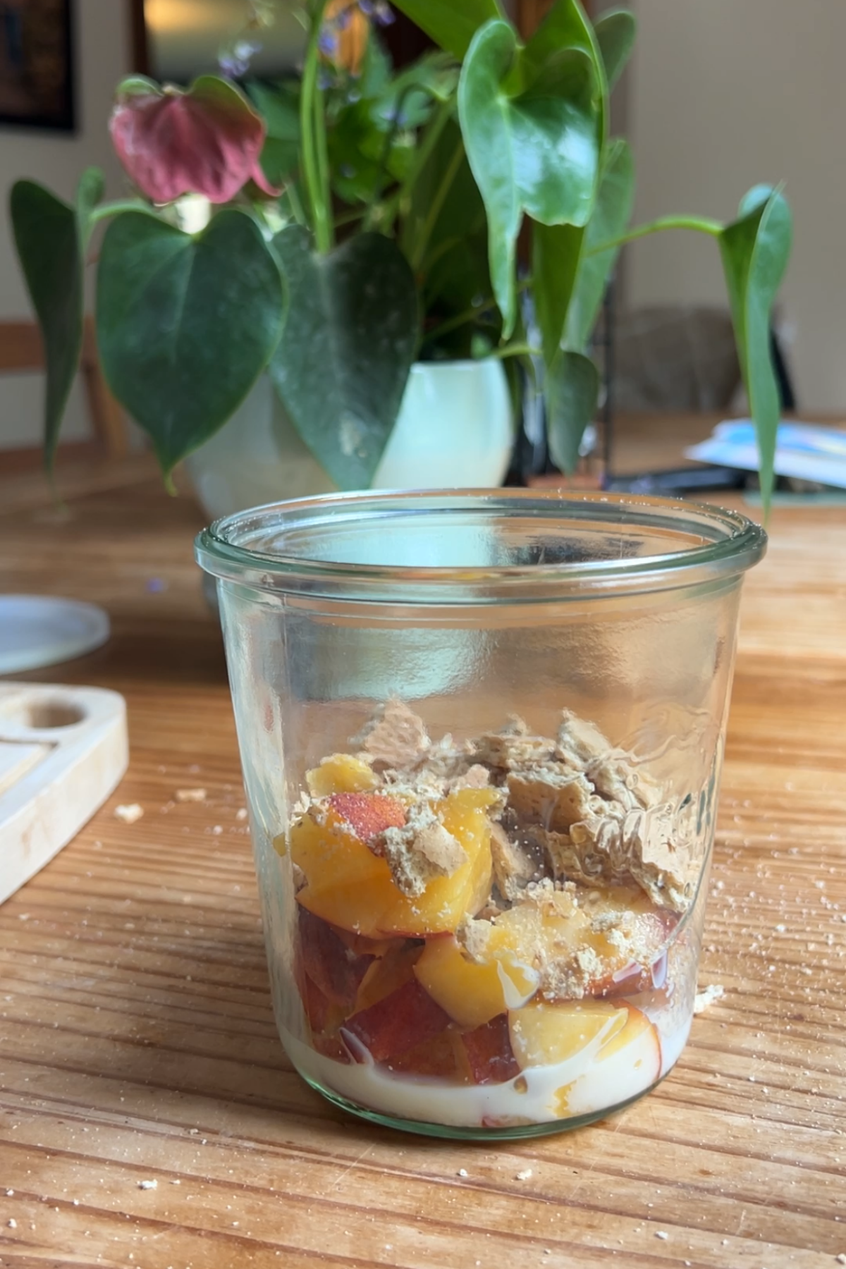 A jar with chopped peaches and crushed graham cracker.