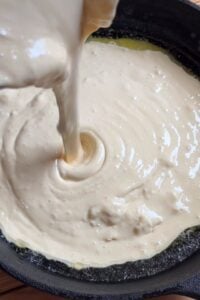 Batter being poured into the cast iron.