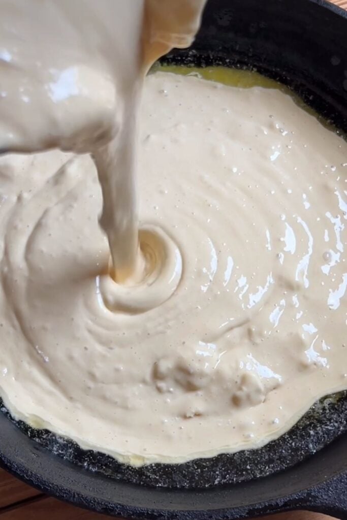 Batter being poured into the cast iron.