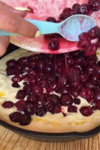 Cherries being poured on top of the batter.
