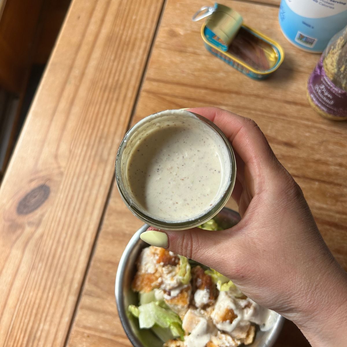 Hand holding the caesar dressing.