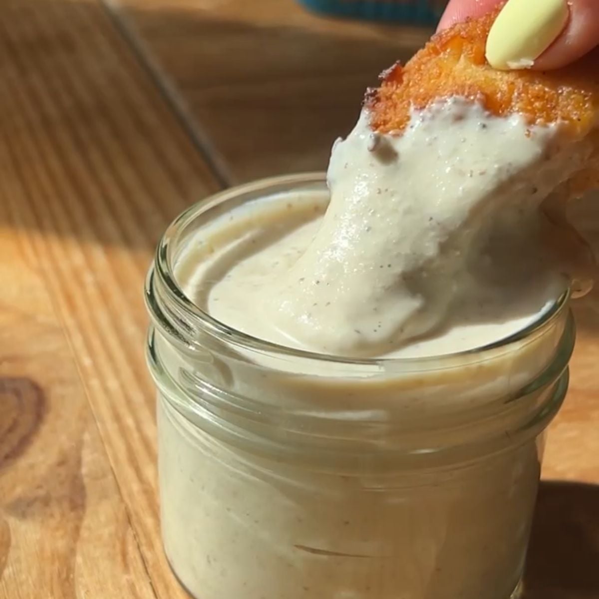Dipping chicken into the greek yogurt caesar dressing.
