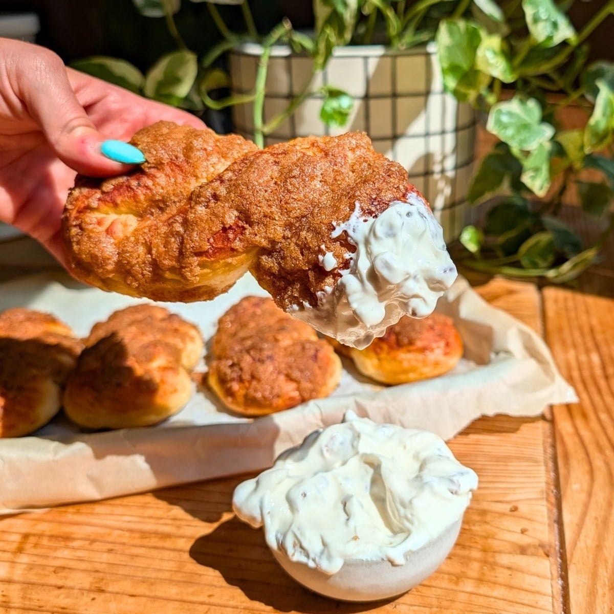 Hand holding a bagel twist dipped in honey walnut cream cheese.