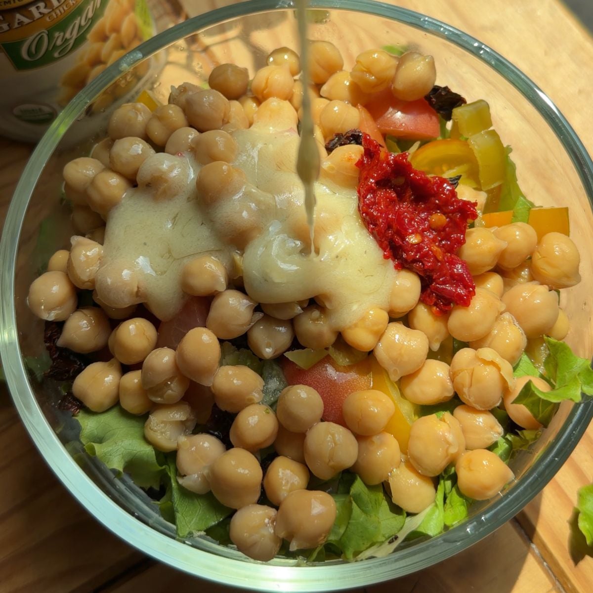 A bowl with dressing being poured in.