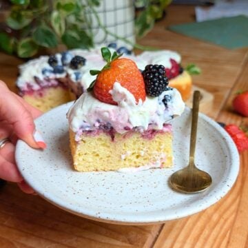 Hand holding the berry pound cake on a plate.
